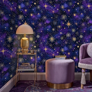 May include: A room with a celestial theme, featuring a dark blue and purple starry wallpaper. A gold lamp sits on a gold side table with books. A purple velvet ottoman and chair complete the decor. The room has a cozy and elegant atmosphere.