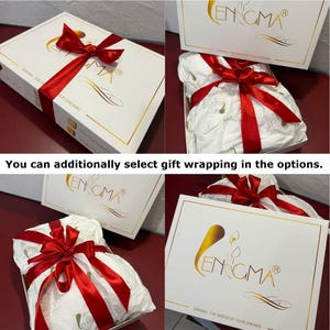 May include: White gift boxes with gold trim and a red satin ribbon. The boxes have the brand name "ENIGMA" printed on them. The gift is wrapped in white tissue paper and tied with a red ribbon. The text "You can additionally select gift wrapping in the options" is also visible.
