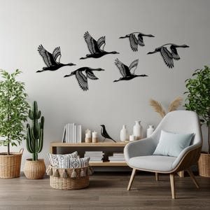 Pode incluir: Arte de parede em metal preto com seis gansos em voo. Os gansos são retratados com designs de asas detalhados, criando uma exibição dinâmica e artística. Esta peça decorativa adiciona um toque de elegância inspirada na natureza.