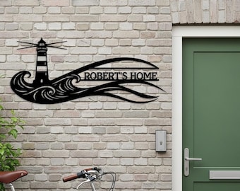 May include: Black metal wall art featuring a lighthouse design with the text "ROBERT'S HOME". The lighthouse has black and white stripes and is set against a wave motif. Mounted on a brick wall.