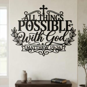 May include: A black metal wall sign featuring the text ALL THINGS POSSIBLE With God and MATTHEW 19:26. The design includes a cross at the top, decorative flourishes, and leafy branches on the sides, all arranged in a symmetrical, cutout style.