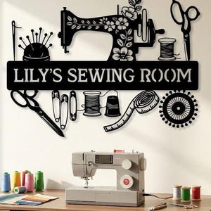 May include: A black metal wall sign featuring the text LILY'S SEWING ROOM, decorated with silhouettes of a sewing machine, scissors, spools of thread, a pincushion, safety pins, and a measuring tape, positioned above a sewing machine on a desk.