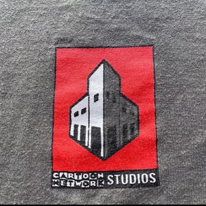 May include: A red square with a white building inside. The building has a flat roof and a window on each side. The text "Cartoon Network Studios" is printed below the building.