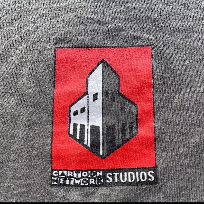 May include: A red square with a white building inside. The building has a flat roof and a window on each side. The text "Cartoon Network Studios" is printed below the building.
