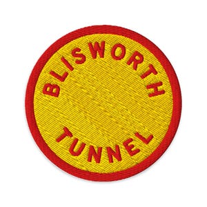 Pode incluir: Um emblema bordado circular com um centro amarelo brilhante e uma borda vermelha espessa. O texto BLISWORTH TUNNEL está bordado em letras maiúsculas vermelhas, curvando-se ao longo das bordas superior e inferior do fundo circular.