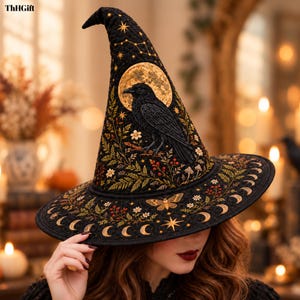May include: A black quilted witch hat featuring an embroidered design of a raven perched on a branch in front of a gold moon. The hat is decorated with botanical elements, a moth, stars, and a moon phase border along the wide brim. Text reads ThHGift.