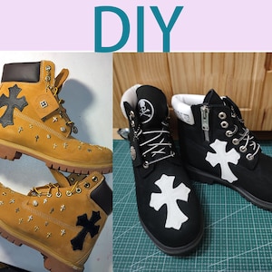 May include: DIY custom designed black and tan Timberland boots with a white cross design. The boots have a zipper on the side and a skull and crossbones design on the back.