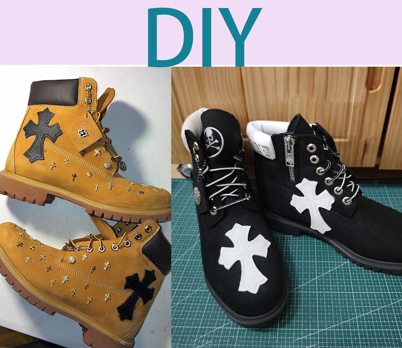 May include: DIY custom designed black and tan Timberland boots with a white cross design. The boots have a zipper on the side and a skull and crossbones design on the back.
