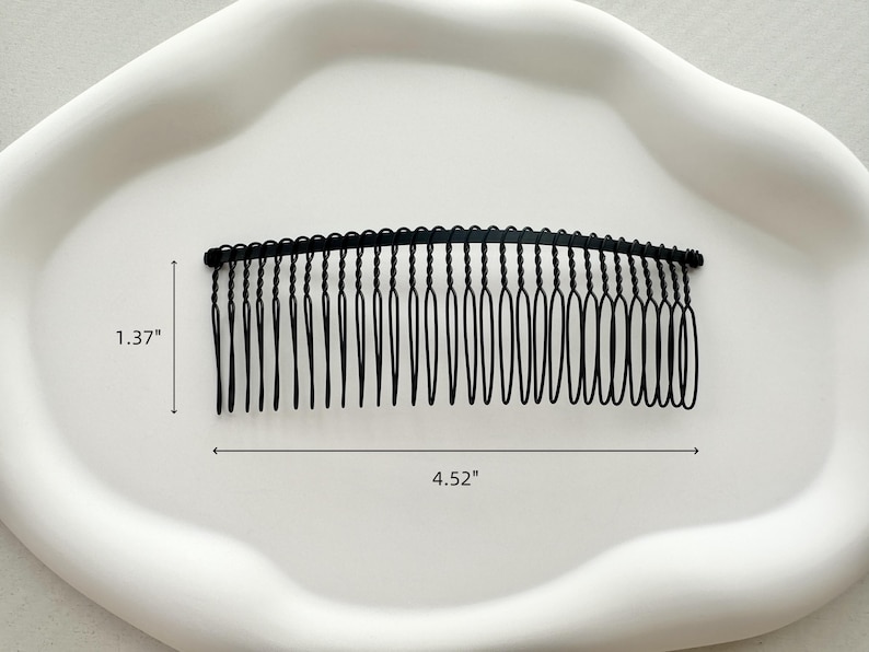 May include: Black metal hair comb with a wavy design. The comb is 4.52 inches long and 1.37 inches wide.
