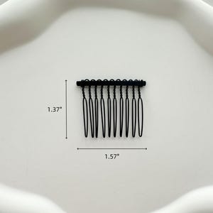 May include: Black metal hair comb with 9 teeth, measuring 1.37 inches tall and 1.57 inches wide.