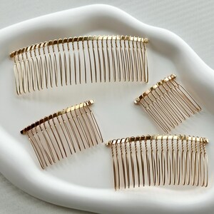 May include: Four gold metal hair combs of varying sizes. The combs are all in the shape of a half-circle and have a fine-toothed design.