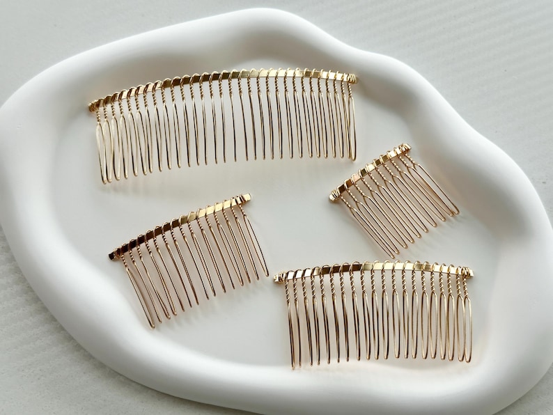 May include: Four gold metal hair combs of varying sizes. The combs are all in the shape of a half-circle and have a fine-toothed design.