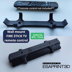 Puede incluir: Un soporte de pared impreso en 3D para un mando a distancia de Fire Stick TV. El soporte es negro y tiene una ranura para que el mando se deslice. El texto "DIGITAL STL file" está impreso en verde sobre fondo blanco. El texto "DESIGNED BY ESAPRINT3D" está impreso en blanco sobre fondo negro.