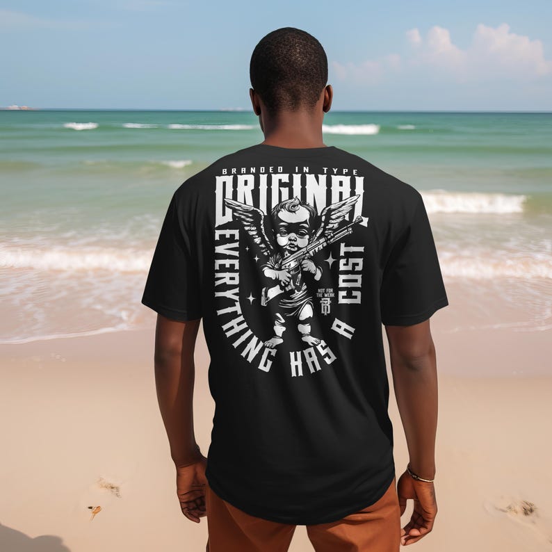 Puede incluir: Camiseta negra con un gr&aacute;fico de un &aacute;ngel sosteniendo un rifle, con las alas extendidas, y el texto "ORIGINAL EVERYTHING HAS A COST". La camiseta es de tipo "branded" y tiene un dise&ntilde;o &uacute;nico.
