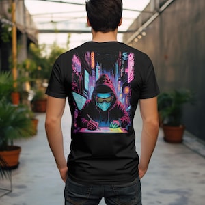 Puede incluir: Camiseta negra con un gráfico de neón de una figura encapuchada con gafas y una máscara, dibujando en un entorno urbano futurista. El diseño incorpora vibrantes tonos rosa, azul y morado, creando una estética cyberpunk.