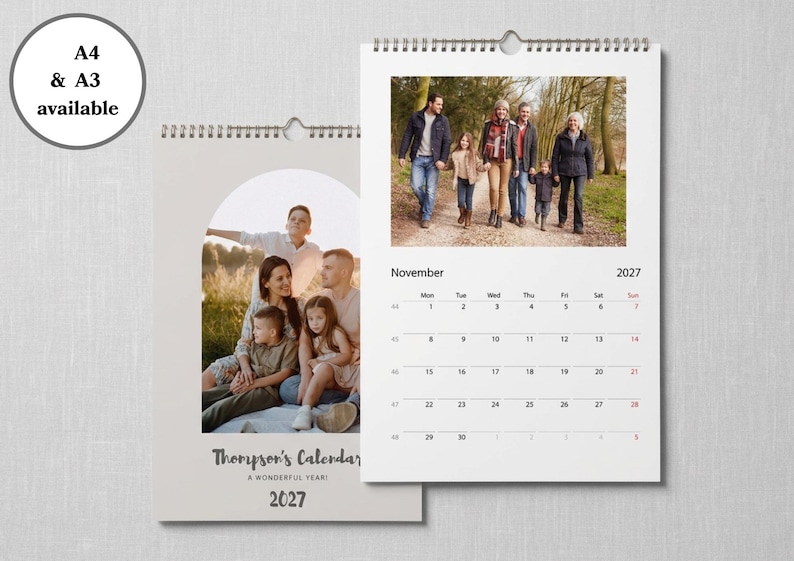 May include: A wall calendar for 2027 featuring a spiral binding and a hanger. The cover displays a family photo in an arch frame with the text Thompson's Calendar A wonderful year! 2027. The open page shows a November 2027 grid and a family photo.