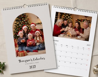 Könnte beinhalten: Ein Wandkalender für 2027 mit Spiralbindung. Das Deckblatt zeigt ein bogenförmiges Foto einer Familie in Weihnachtspullovern und Weihnachtsmützen. Die Innenseite zeigt ein Kalenderblatt für November 2027 und ein Lebkuchenhaus-Motiv.