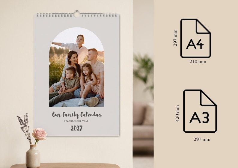 May include: A wall calendar with a spiral binding featuring a family photo inside an arch-shaped frame. The text reads Our Family Calendar, A WONDERFUL YEAR!, and 2027. Size options include A4 at 210 mm by 297 mm and A3 at 297 mm by 420 mm.