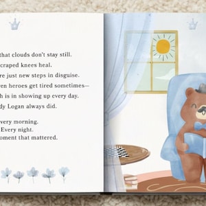 Puede incluir: Una p&aacute;gina de libro infantil con texto sobre pap&aacute; Logan y una ilustraci&oacute;n de un oso pardo grande con sombrero y pajarita azul sentado en un sill&oacute;n azul con un oso peque&ntilde;o, ambos leyendo un libro azul en una habitaci&oacute;n con una ventana.