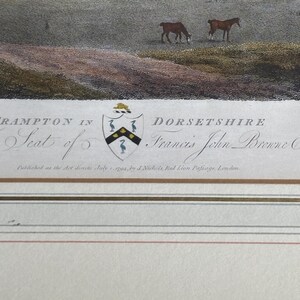 May include: An antique print depicting a pastoral scene with horses grazing in a field. The print includes text that reads "FRAMPTON IN DORSETSHIRE" and "The Seat of Francis John Browne Esq.". The print has a crest and is framed with decorative lines.
