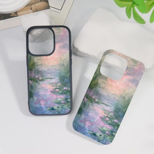 May include: Two phone cases with a watercolor painting of a pond with lily pads and pink flowers. The cases are black and have a clear back.