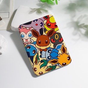 May include: A rectangular phone case featuring a colorful cartoon design of various Pokémon characters. The case has a yellow background and showcases characters like Eevee, Umbreon, and Sylveon. The case is made of a smooth material.