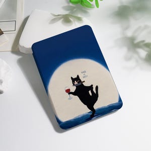 May include: A navy blue case featuring a black cat balancing on one leg, holding a wine glass and a knife in its mouth. The cat is set against a backdrop of a full moon and a dark blue sky. The text "TAKE IT EASY" is above the cat.