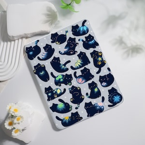 May include: A light grey tablet case with a pattern of black cat illustrations with colourful accents. The cats are in various poses, some with floral or star-like designs. The case is designed to protect a tablet.