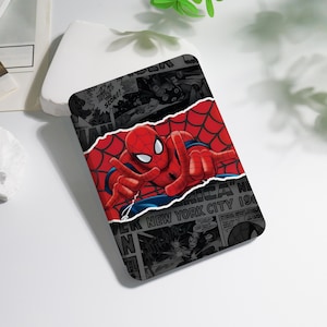 Peut inclure: Un étui rectangulaire avec Spider-Man en costume rouge et bleu, sur un fond de toile d'araignée rouge. Le design comprend des panneaux de bande dessinée en noir et blanc. Le texte comprend "NEW YORK CITY 190".