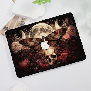 May include: A laptop skin featuring a dark, detailed illustration of a moth with patterned wings centered above a human skull. The design includes a large full moon, crescent moons, and clusters of deep red and pink roses against a starry background.