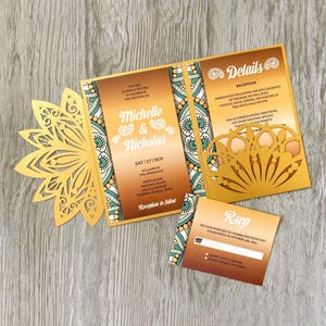 May include: A gold and brown wedding invitation suite with a floral laser-cut design. The invitation includes details for Michelle and Nicholas's wedding, with an RSVP card and reception information. The suite is on a wooden surface.