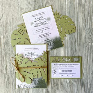 Puede incluir: Una invitación de boda verde y blanca con un tema tropical. La invitación presenta un diseño recortado de hojas de monstera y el texto "You are joyfully invited to celebrate the wedding of Kimberly Marie Uftring and Christopher William Shingler".