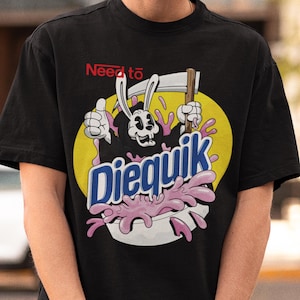 Puede incluir: Camiseta negra con un gráfico de un Grim Reaper de dibujos animados sosteniendo una guadaña y un tazón de cereal rosa. El texto "Need to Diequik" está impreso en el tazón de cereal.
