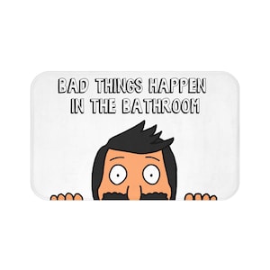 May include: White rectangular bath mat with the text "BAD THINGS HAPPEN IN THE BATHROOM". The mat features a cartoon character with black hair, a mustache, and large eyes.
