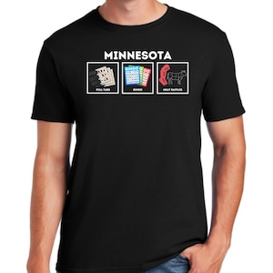 Puede incluir: Camiseta negra con la palabra "MINNESOTA" sobre tres imágenes. Las imágenes representan rasca y gana, cartones de bingo y un diagrama de rifa de carne. La camiseta es de cuello redondo.
