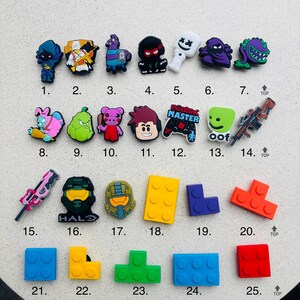 May include: Twenty-five colourful shoe charms featuring popular video game and internet characters, including Roblox, Fortnite, and Minecraft. The charms are made of rubber and have a variety of shapes and designs.