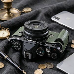 May include: A black Nikon Z fc mirrorless camera with olive green textured leather accents, featuring a prominent lens, multiple manual control dials on the top plate, a hot shoe mount, and the Nikon logo printed in white on the front prism housing.