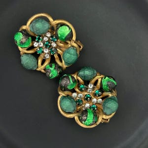 Puede incluir: Un par de pendientes de clip en tono dorado con esmalte verde y negro y diamantes de imitación transparentes y verdes.
