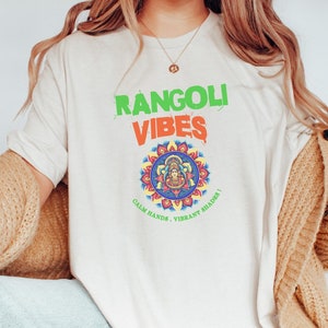 May include: A white t-shirt with the text "Rangoli Vibes" in green and orange lettering. A colourful mandala design with the text "Calm Hands, Vibrant Shades!" is below the text.