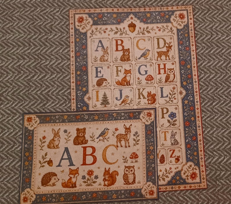 May include: Two rectangular prints featuring an alphabet theme with woodland animals and botanical motifs. The designs include letters A through Z, illustrated with creatures like bears, foxes, owls, and deer, framed by a blue floral border.