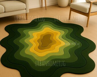 Può includere: Un tappeto astratto a strati nei toni del verde e del giallo, che ricorda una mappa topografica. Il tappeto ha una forma organica unica ed è posizionato su un pavimento in legno chiaro. Il testo "URBANHOMERUG" è visibile sul tappeto.