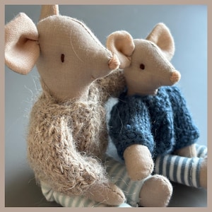 May include: Two plush mouse dolls made of beige fabric with embroidered eyes and noses. The larger mouse wears a chunky beige knit sweater, while the smaller mouse wears a dark blue knit sweater. Both mice wear light blue and white striped pants.