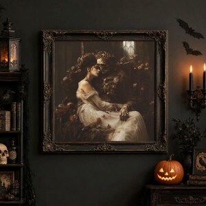 May include: A square framed wall art piece featuring a dark, romantic painting of a person in a white gown embracing a skeletal figure adorned with flowers. The ornate, dark-toned frame surrounds the detailed, moody artwork in a gothic style.