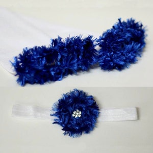 May include: A white headband with a blue fuzzy flower with a rhinestone center.