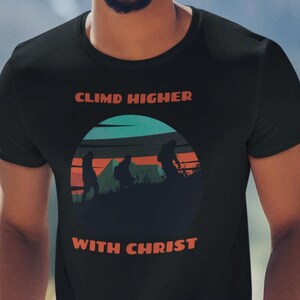 May include: Black t-shirt with a retro-style graphic of people hiking with the text "Climb Higher with Christ".