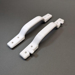 May include: Two white plastic handles with four holes each. The handles are designed for mounting on a surface.
