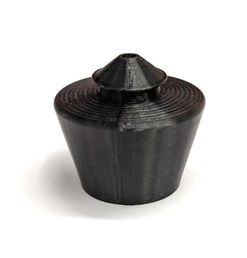 May include: A black plastic bottle stopper with a conical top and a ridged base.