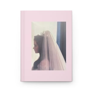 Puede incluir: Un diario rosa con una imagen vintage de una novia de perfil, con tiara y velo. La imagen tiene un fondo suave y claro, creando una estética romántica y elegante.