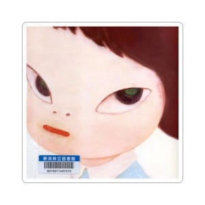 以下が含まれることがあります： 大きな目とわずかにしかめっ面をした子供の顔のクローズアップを特徴とするステッカー。子供は肌が白く、赤い唇と濃い茶色の髪をしています。日本語のテキストが入った青と白のラベルが左下隅にあります。