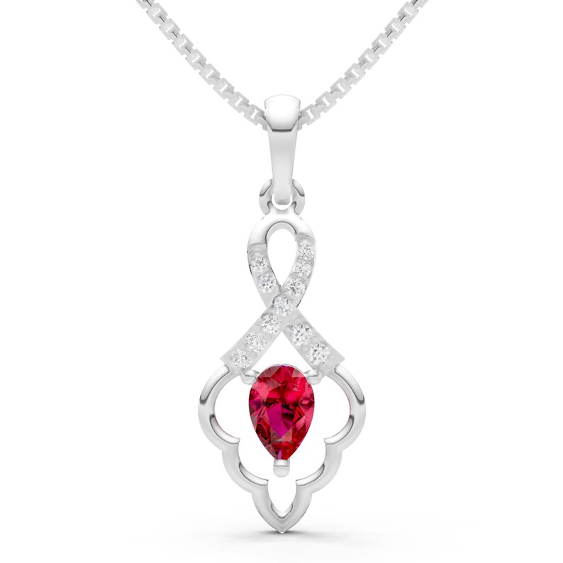 May include: A silver pendant necklace featuring a pear-shaped, deep red gemstone. The pendant has a decorative openwork design with small, clear accent stones and a delicate chain.